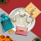 Elegant and spiritual Rakhi gift set featuring silver thali, colored powders, Rakhi, and a heartfelt card.