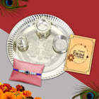 Luxurious Rakhi gift set featuring designer Rakhi, silver-plated 9-inch pooja thali, roli-chawal in golden bowls, and an ornate greeting card celebrating brotherly affection.